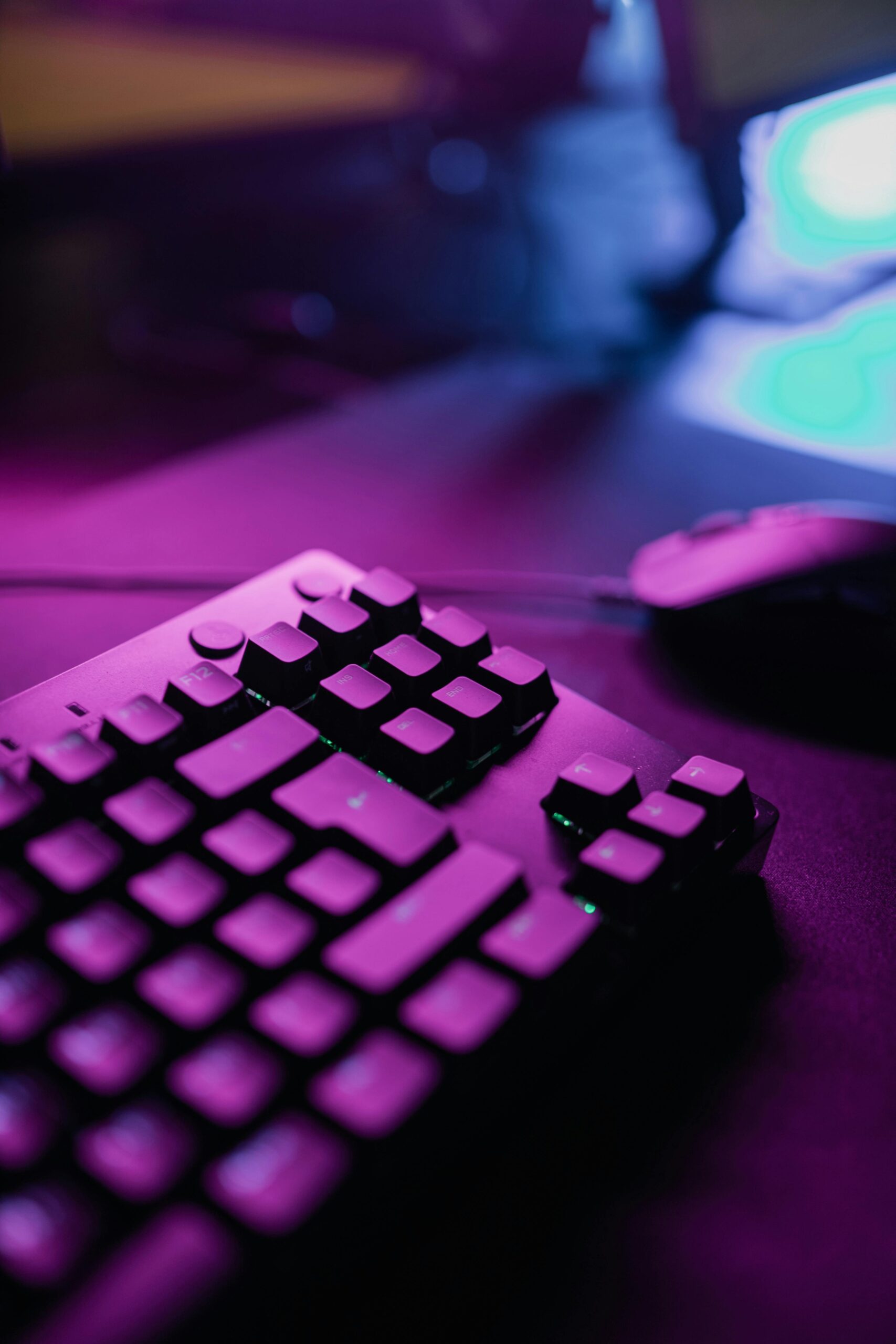 Close-up of a gaming keyboard and mouse illuminated by vibrant pink lighting, creating a dynamic atmosphere.